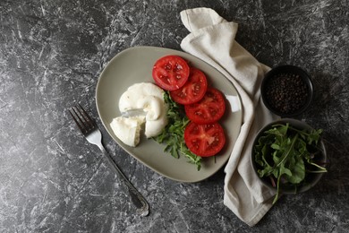 Photo of Delicious burrata cheese with tomatoes, arugula, peppercorns and fork on grey table, flat lay