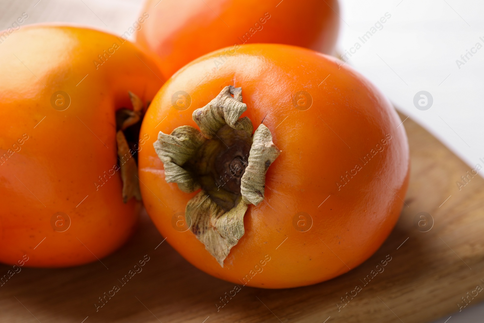 Photo of Board with delicious ripe persimmons on table, closeup