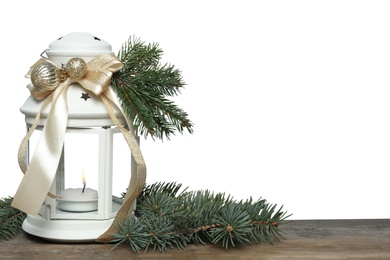 Photo of Christmas lantern with burning candle and fir branches on wooden table, space for text