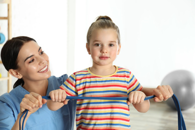 Photo of Orthopedist working with little girl in hospital gym