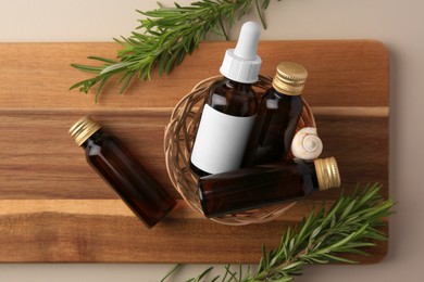 Photo of Bottles of cosmetic products, shell and rosemary on beige background, top view