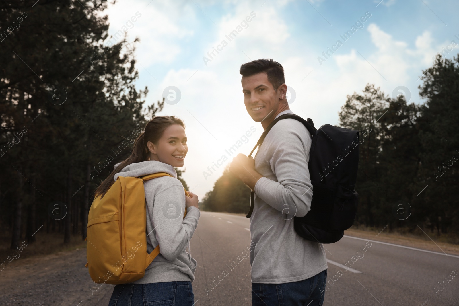 Photo of Happy couple with backpacks on road near forest