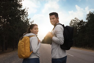 Photo of Happy couple with backpacks on road near forest