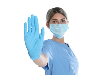 Photo of Doctor in protective mask showing stop gesture on white background. Prevent spreading of coronavirus