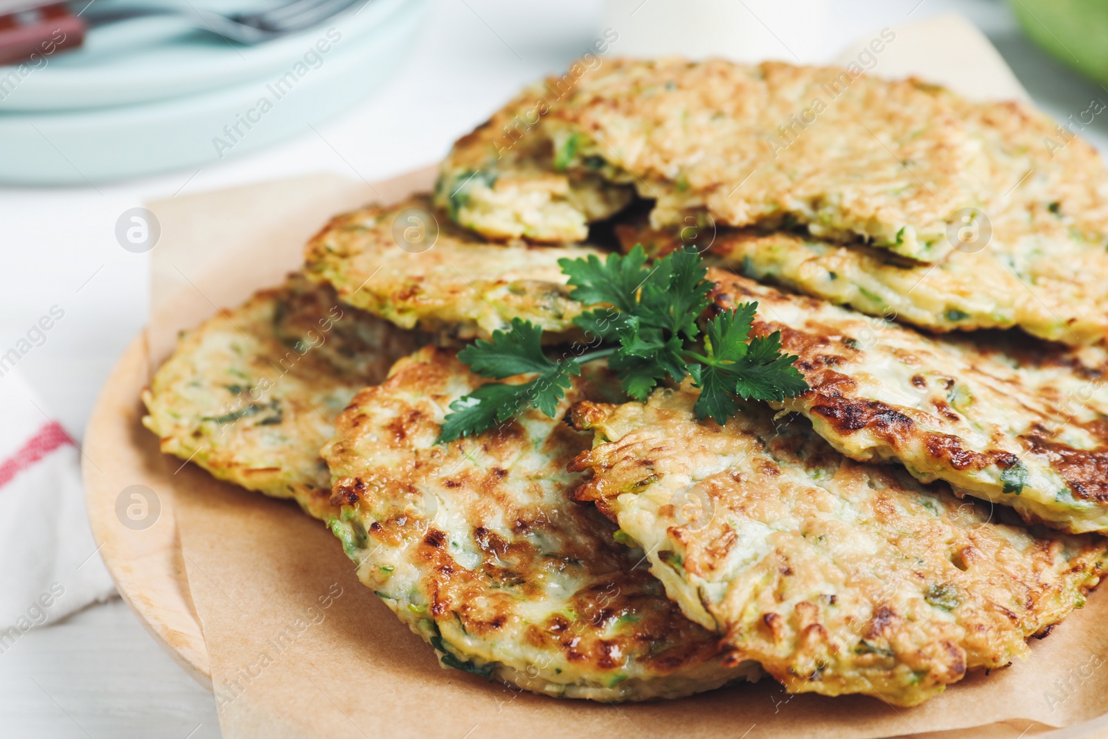 Photo of Delicious zucchini fritters with parsley on plate, closeup