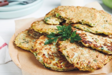 Delicious zucchini fritters with parsley on plate, closeup