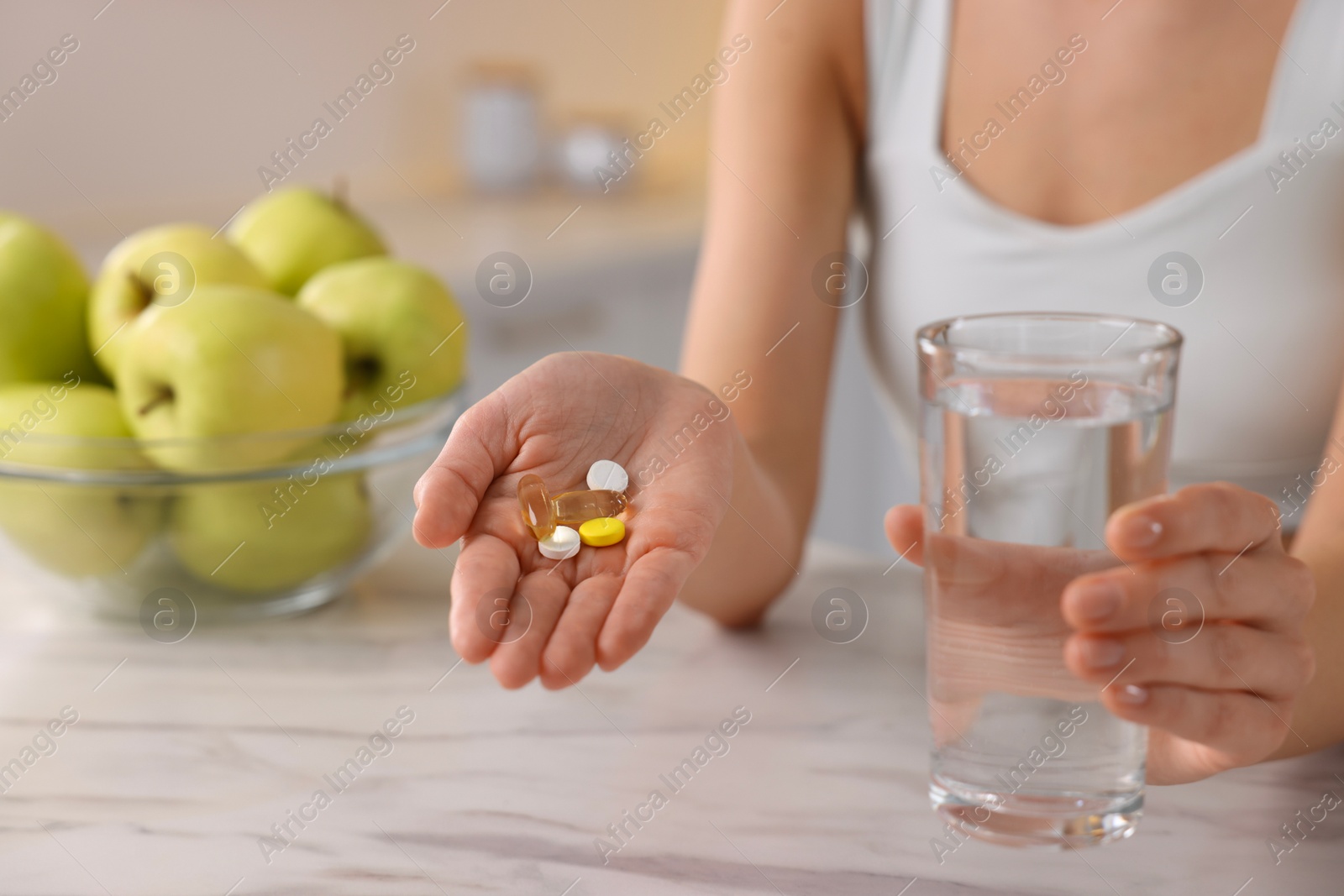 Photo of Woman with glass of water and pills at table indoors, closeup. Weight loss