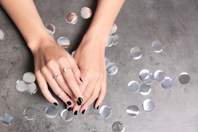 Photo of Woman showing black manicure on grey background, closeup with space for text. Nail polish trends