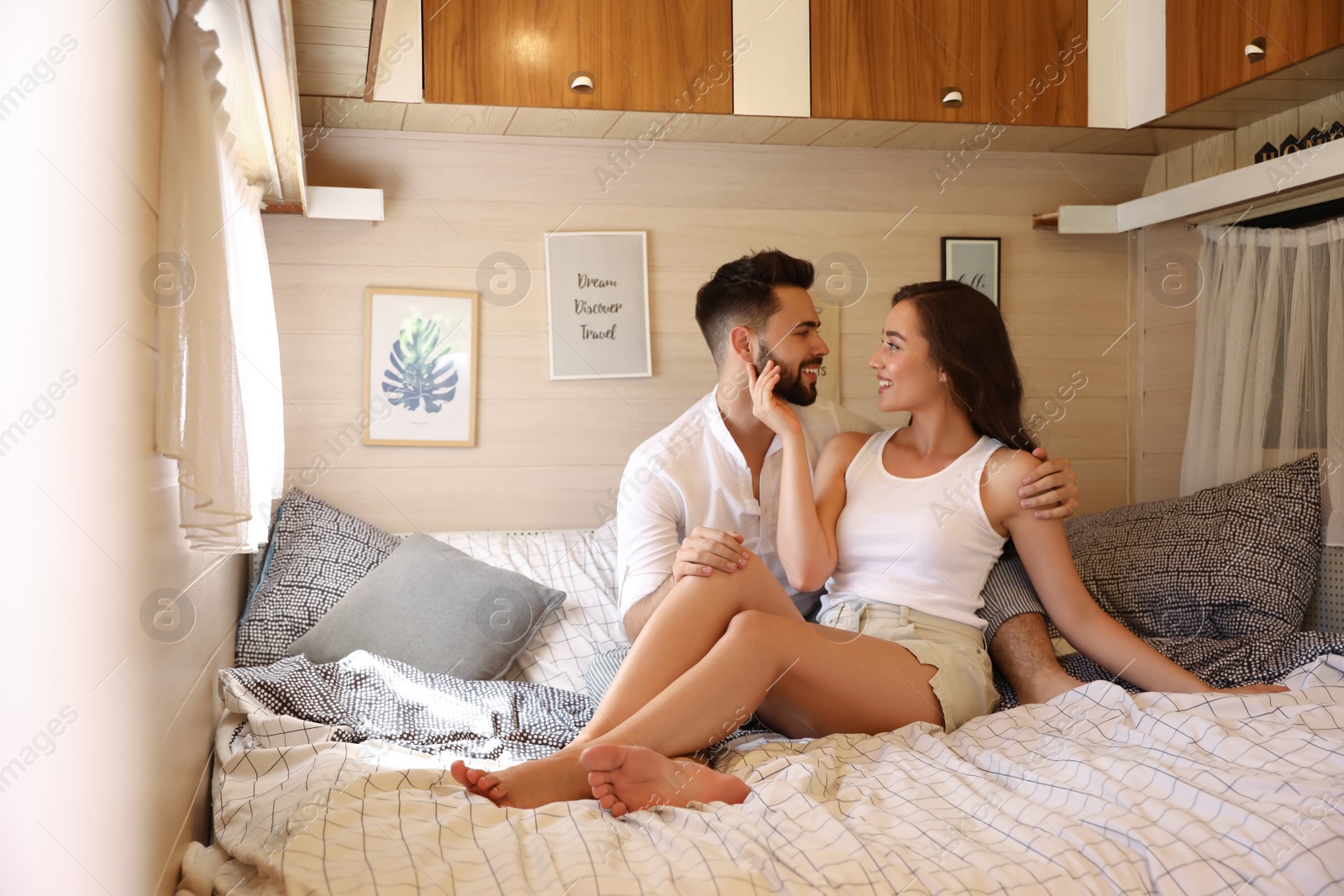 Photo of Happy young couple on bed in trailer. Camping vacation