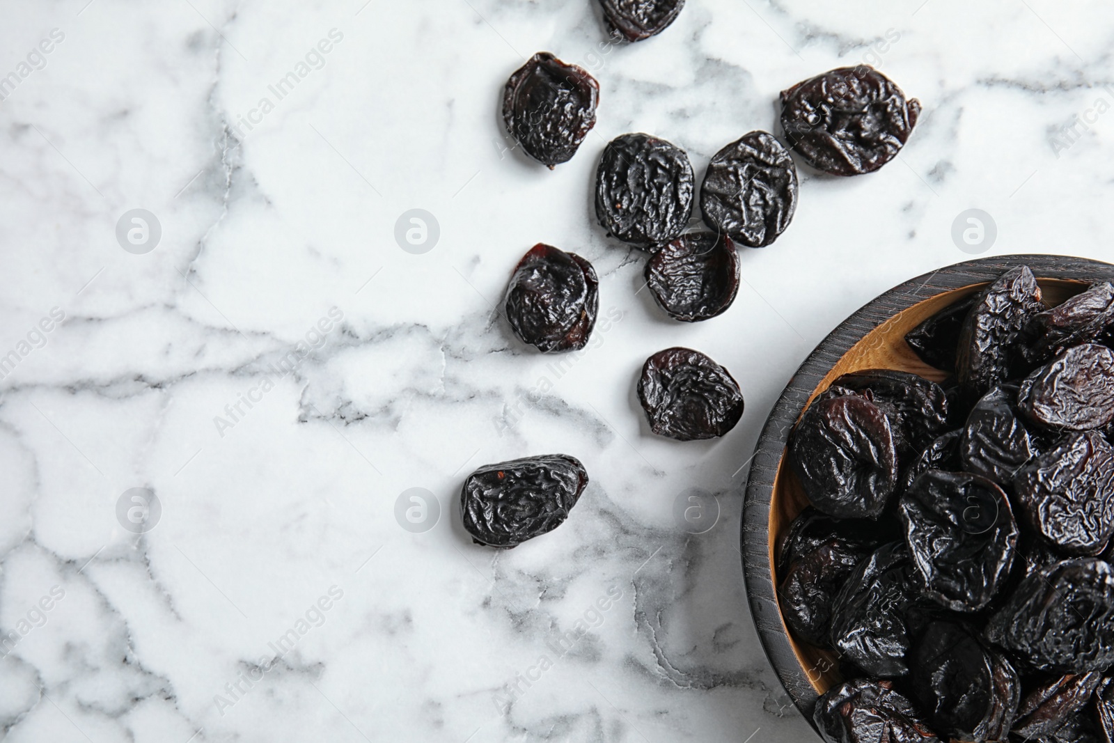 Photo of Plate of sweet dried plums on marble background, top view with space for text. Healthy fruit