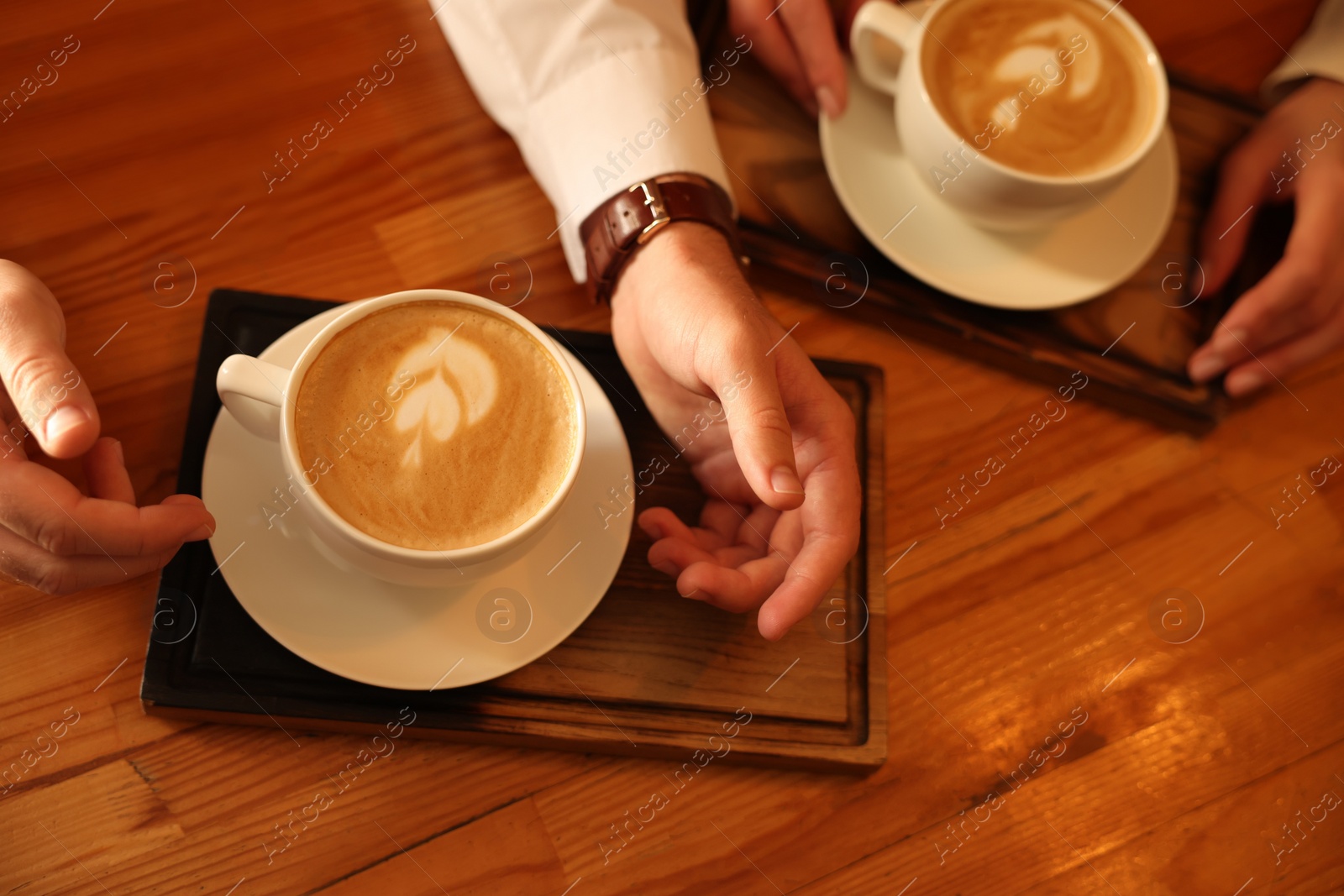 Photo of Couple with cups of aromatic coffee at wooden table, closeup