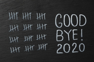 Photo of Crossed out sticks and text Goodbye 2020 on black chalkboard