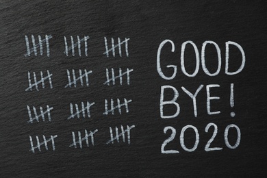 Crossed out sticks and text Goodbye 2020 on black chalkboard