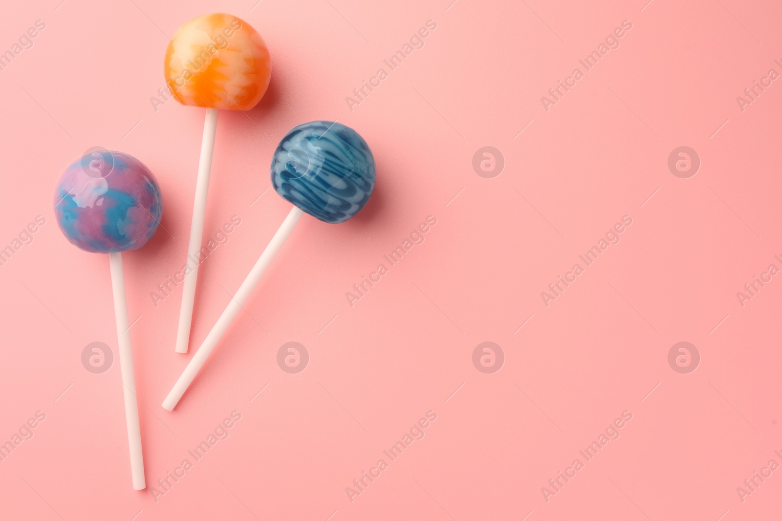 Photo of Tasty lollipops on pink background, flat lay. Space for text