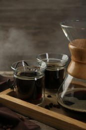 Photo of Glass chemex coffeemaker with coffee and beans on wooden table