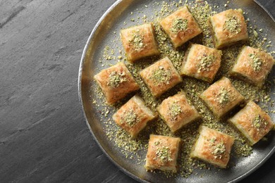 Delicious fresh baklava with chopped nuts on grey table, top view and space for text. Eastern sweets