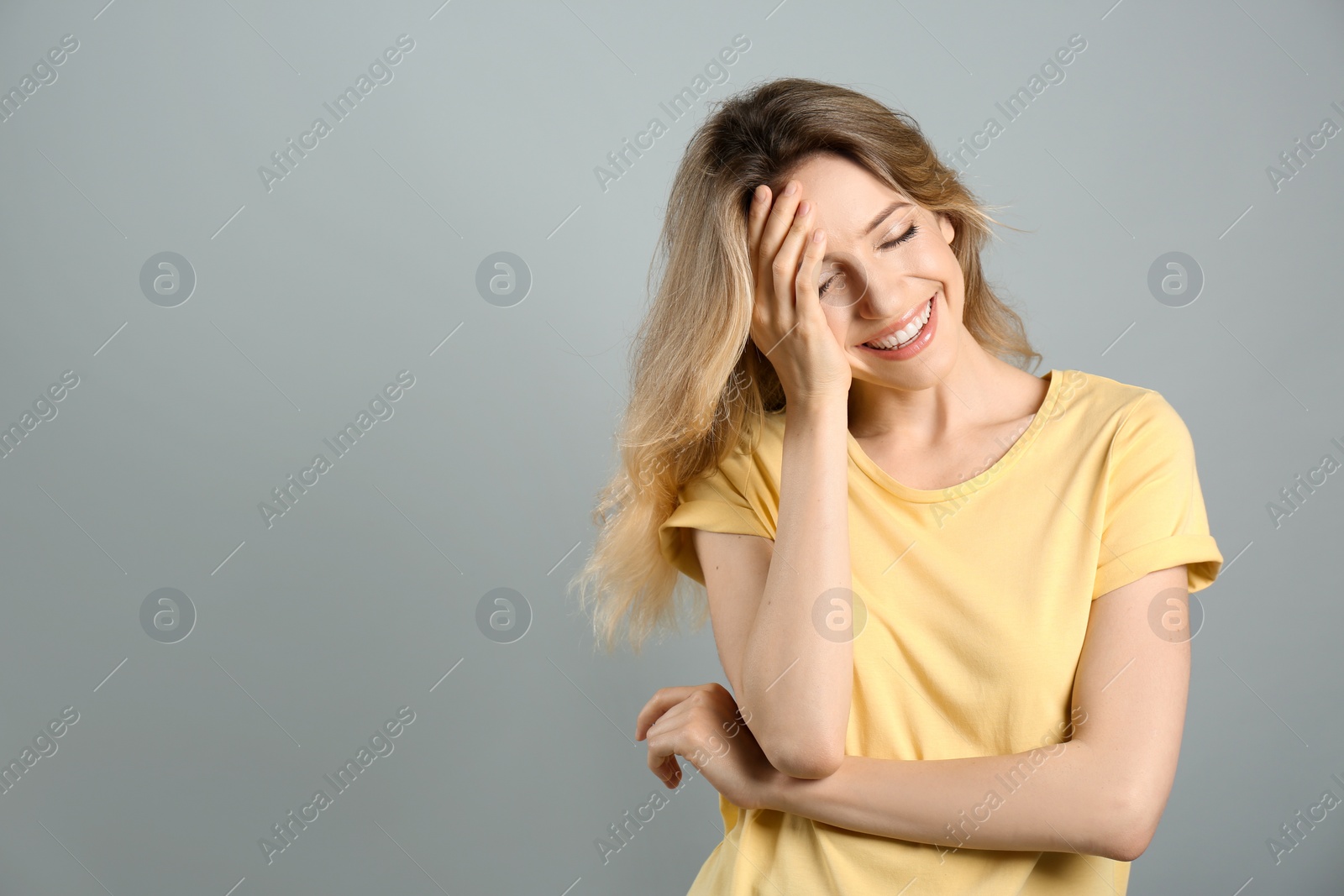 Photo of Portrait of happy young woman with beautiful blonde hair and charming smile on grey background. Space for text