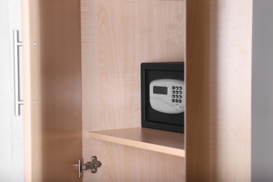Black steel safe with electronic lock in wooden closet at hotel