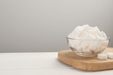 Bowl with sugar cubes on white table. Space for text
