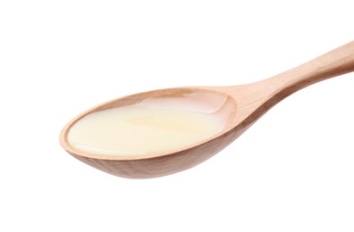 Wooden spoon with condensed milk isolated on white