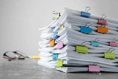 Photo of Stack of documents with binder clips on grey stone table, closeup view. Space for text