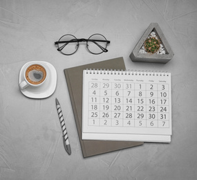 Flat lay composition with calendar and cup of coffee on grey table