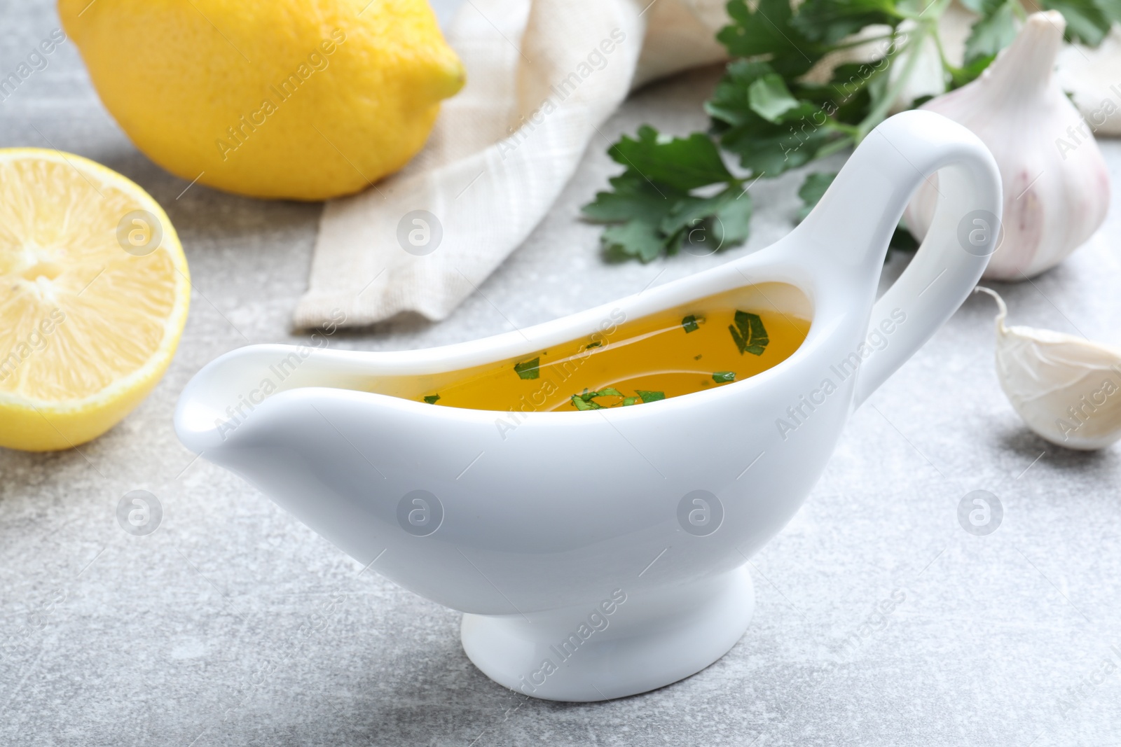 Photo of Ceramic boat with lemon sauce on light table, closeup. Delicious salad dressing