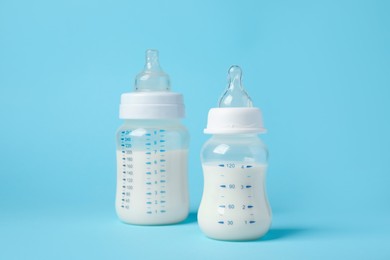 Photo of Feeding bottles with milk on light blue background