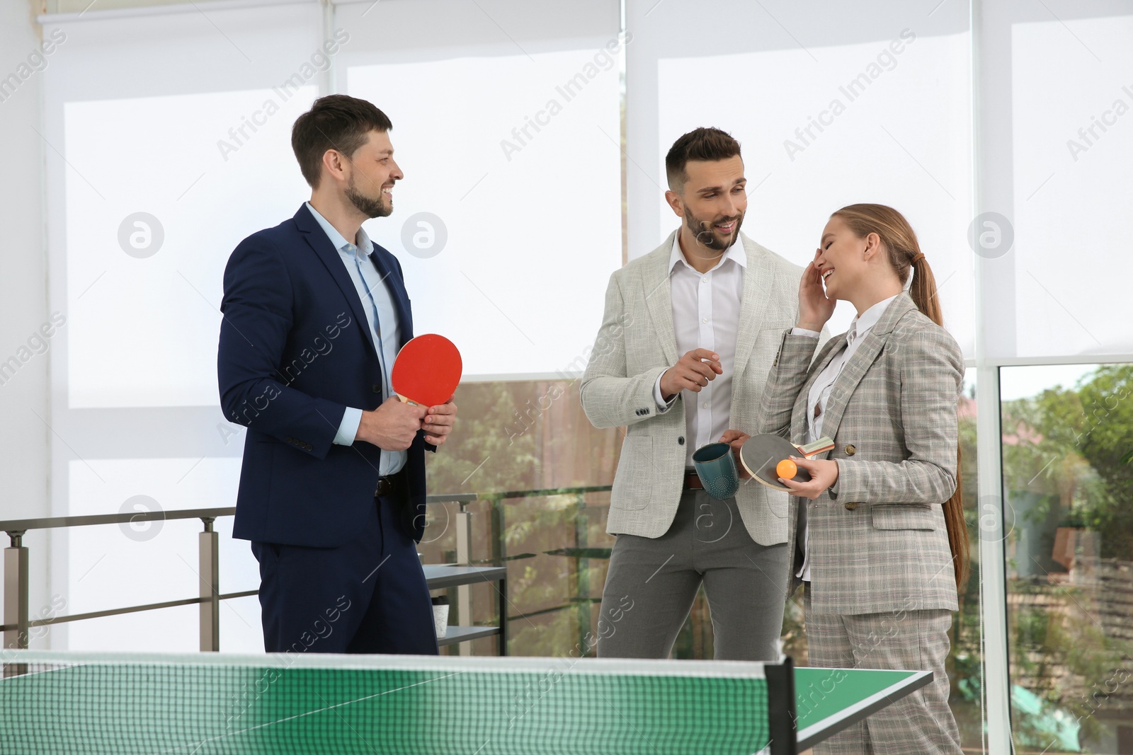 Photo of Business people talking near ping pong table in office