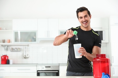 Young athletic man preparing protein shake in kitchen, space for text