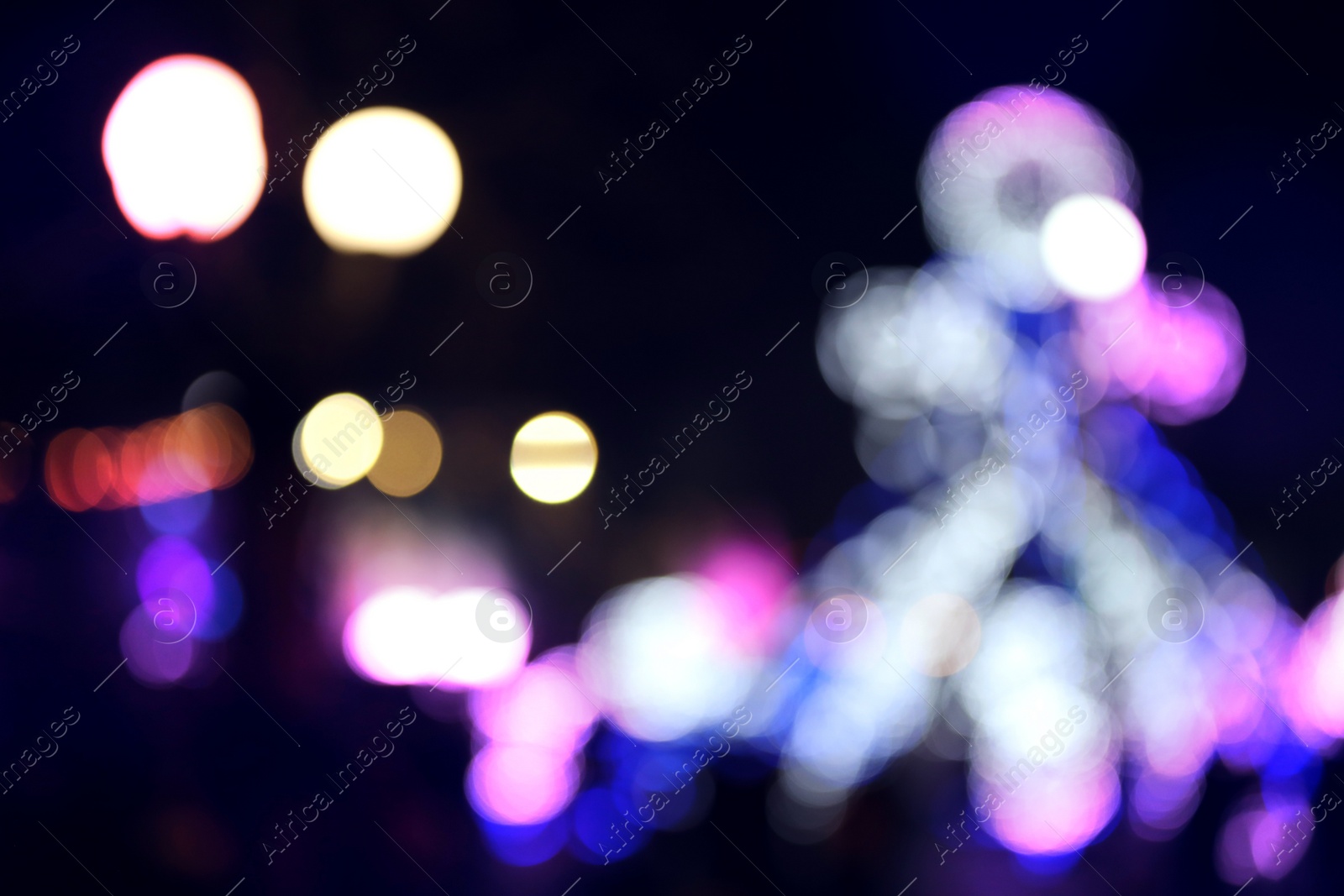 Photo of Blurred view of city street with festive lights at night. Bokeh effect