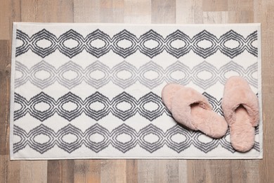 Photo of Soft bath mat and slippers on floor, top view