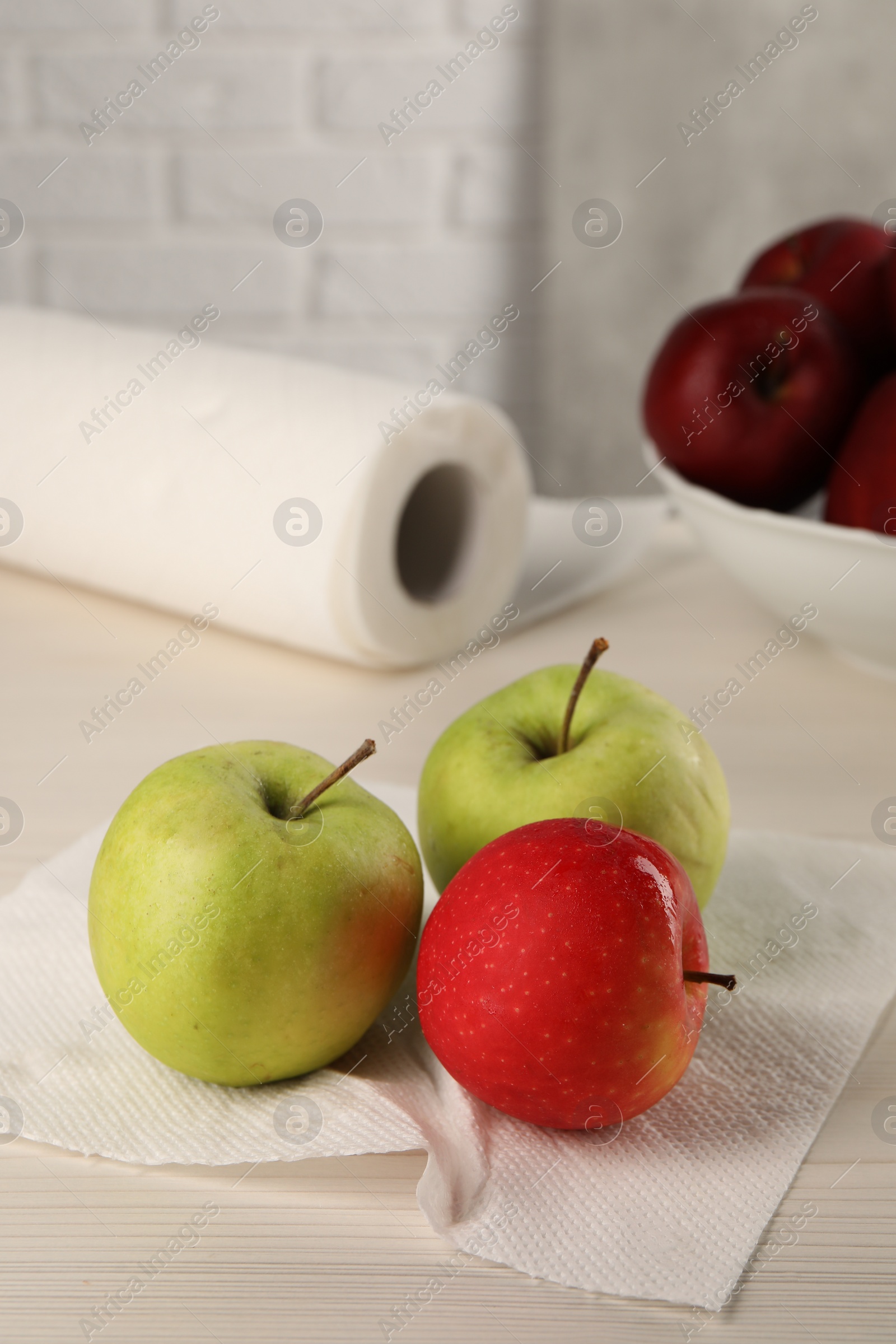 Photo of Fresh apples and paper towel on light wooden table