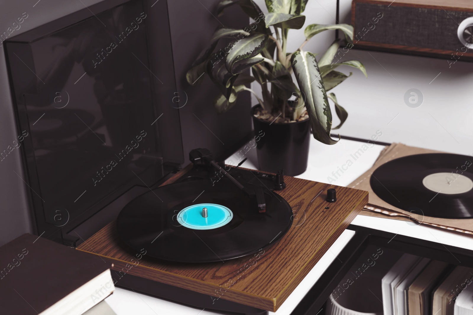 Image of Stylish turntable with vinyl disc near grey wall in room