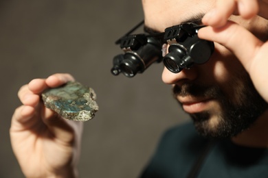 Photo of Male jeweler evaluating semi precious gemstone in workshop, closeup