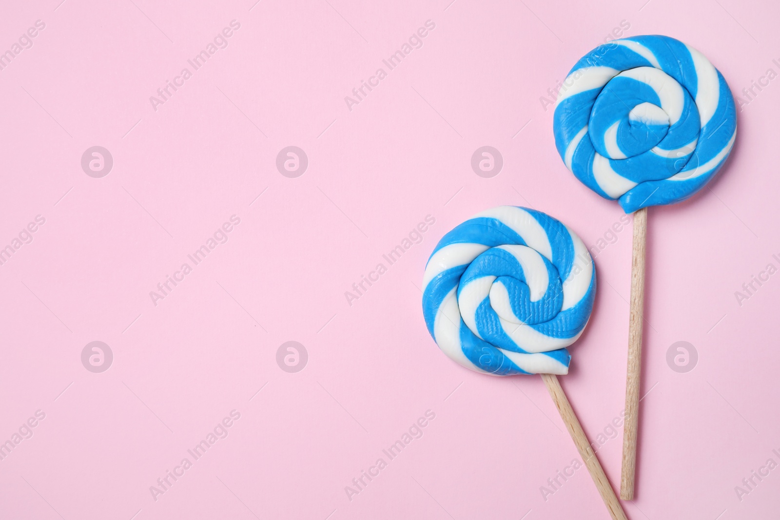 Photo of Sticks with bright lollipops on pink background, flat lay. Space for text