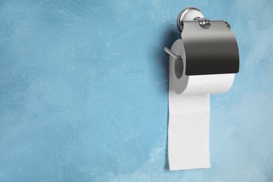 Toilet paper holder with roll on color background. Space for text