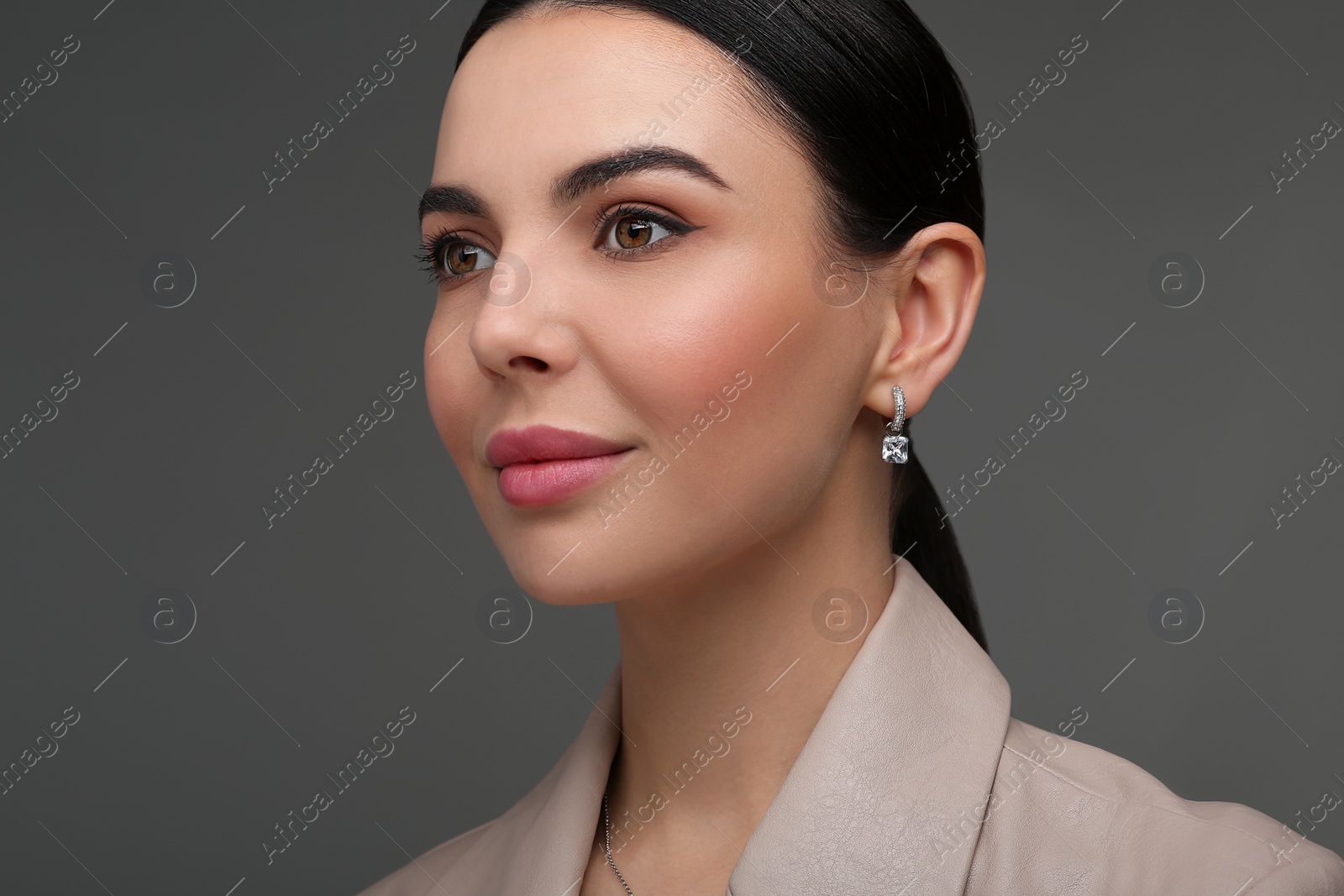 Photo of Beautiful young woman with elegant earrings on dark grey background