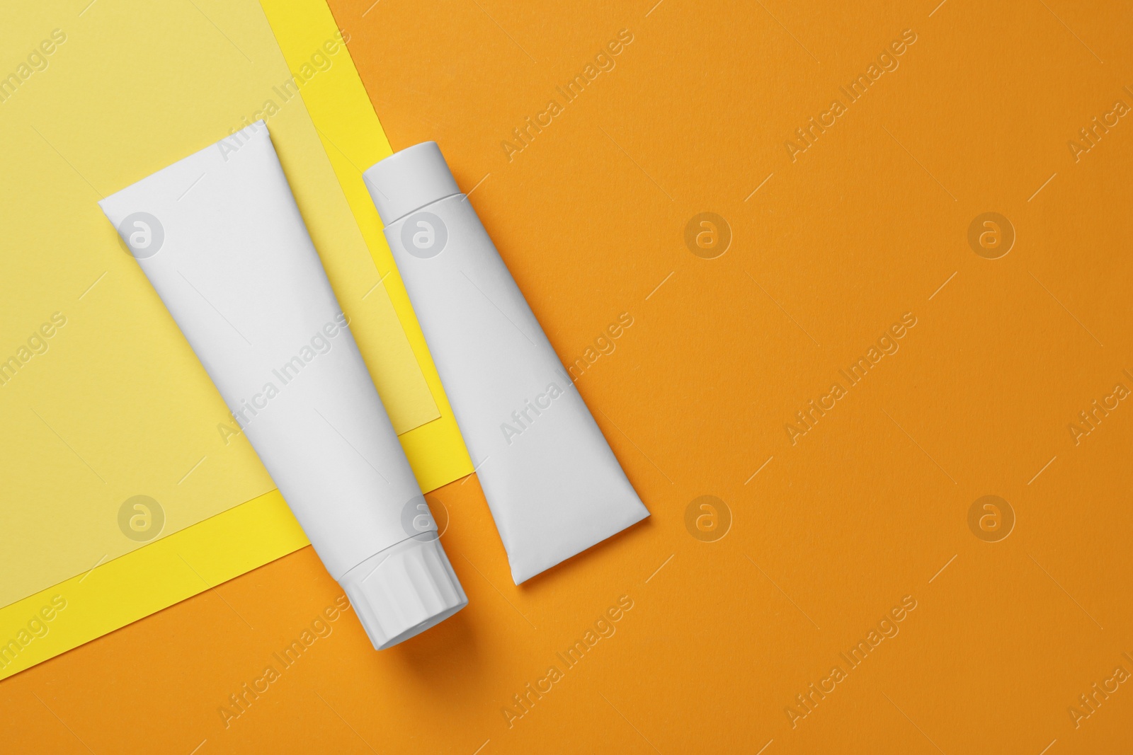 Photo of Blank tubes of toothpaste on color background, flat lay. Space for text