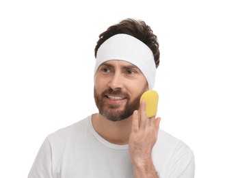 Man with headband washing his face using sponge on white background