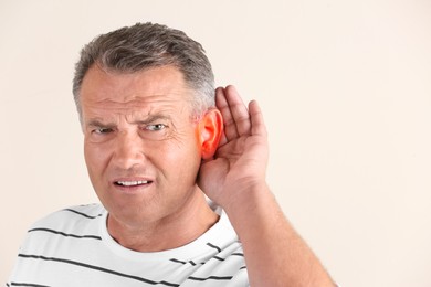 Image of Mature man suffering from earache on light background