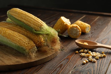 Photo of Tasty sweet corn cobs on wooden table