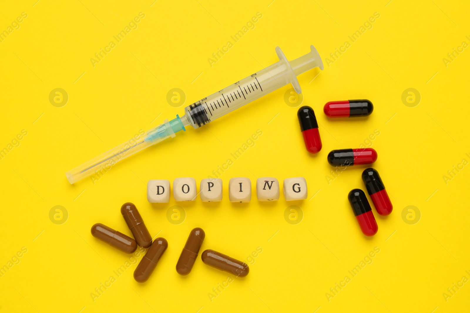 Photo of Wooden cubes with word Doping and drugs on yellow background, flat lay