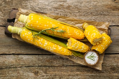 Photo of Tasty cooked corn cobs on wooden table, flat lay