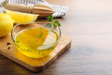 Bowl with lemon sauce and ingredients on wooden table, space for text. Delicious salad dressing