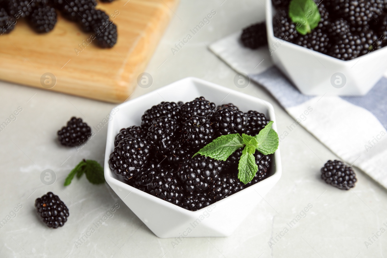 Photo of Bowl of tasty blackberries on grey marble table