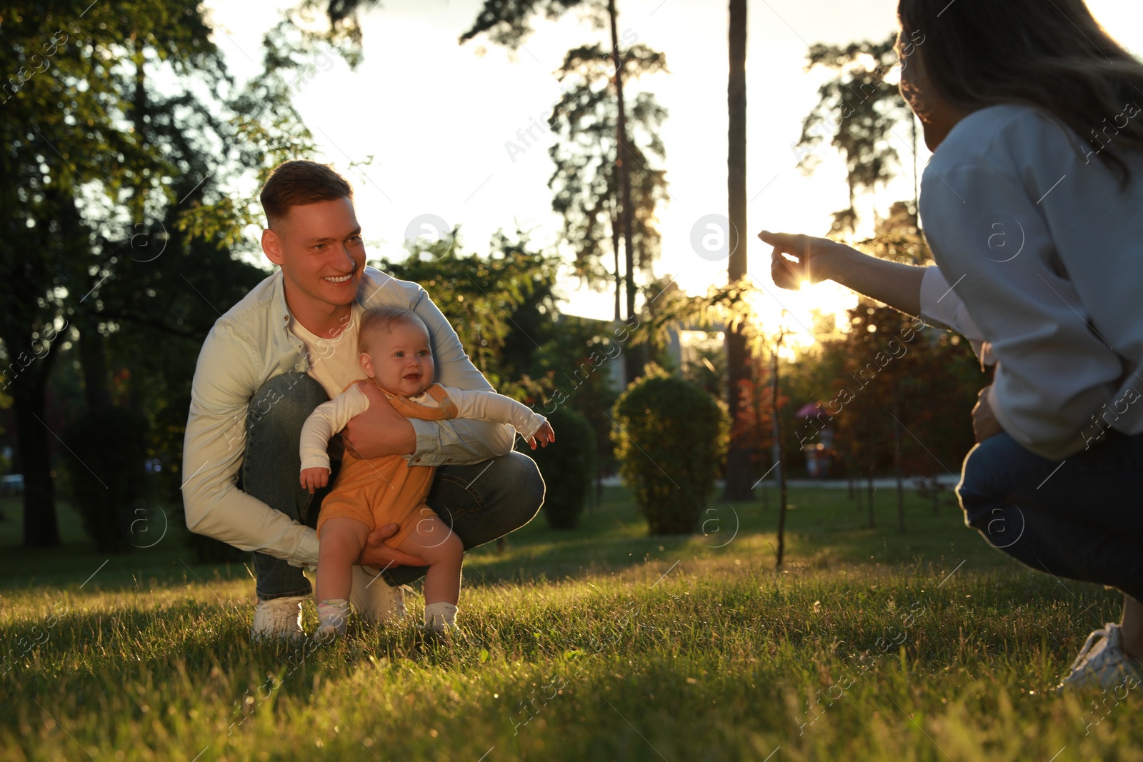 Photo of Parents with their cute daughter spending time together in park on summer day