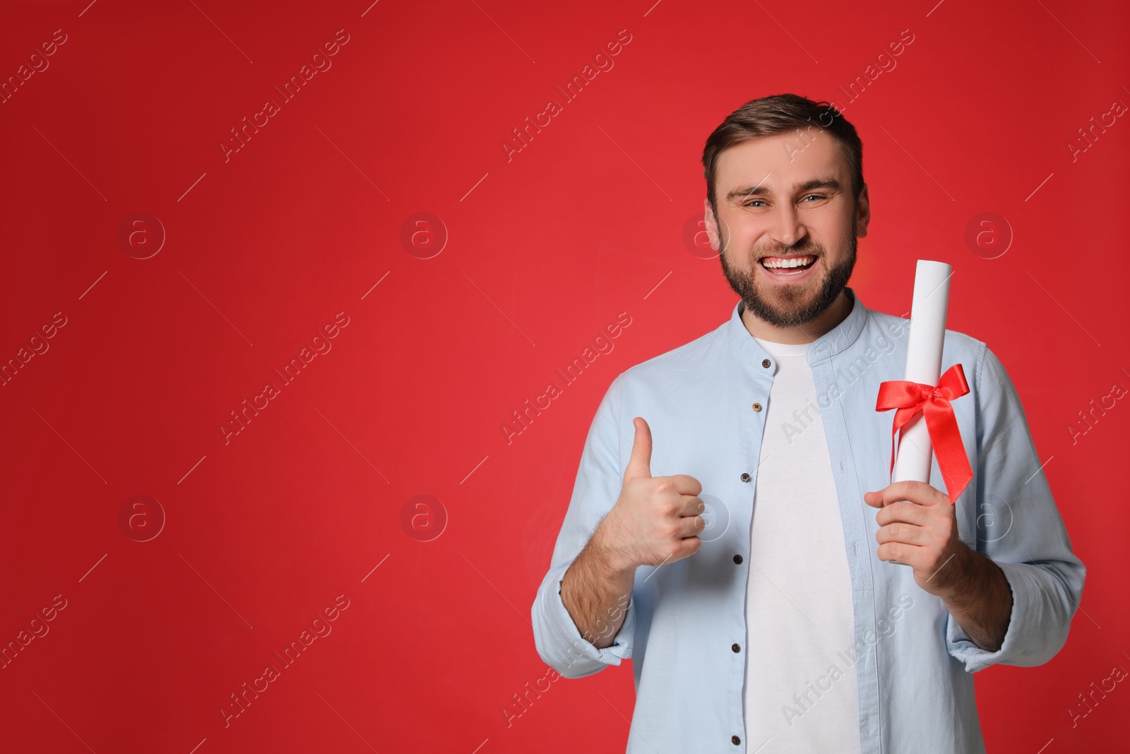 Photo of Happy student with diploma on red background. Space for text