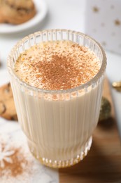 Photo of Glass of delicious eggnog with cinnamon on white table, closeup