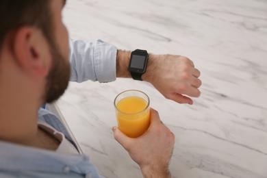 Photo of Young man with smart watch and glass of juice at home, above view